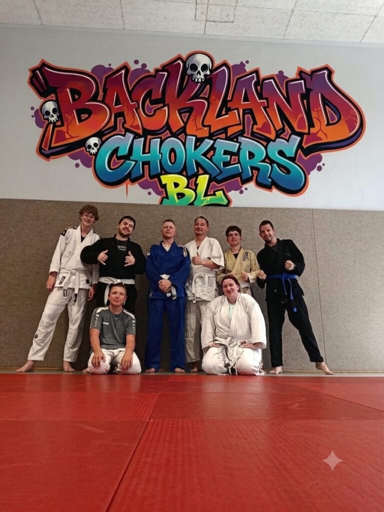 Die BJJ-Gruppe in Kimonos vor dem Wandbild „Backland Chokers BL